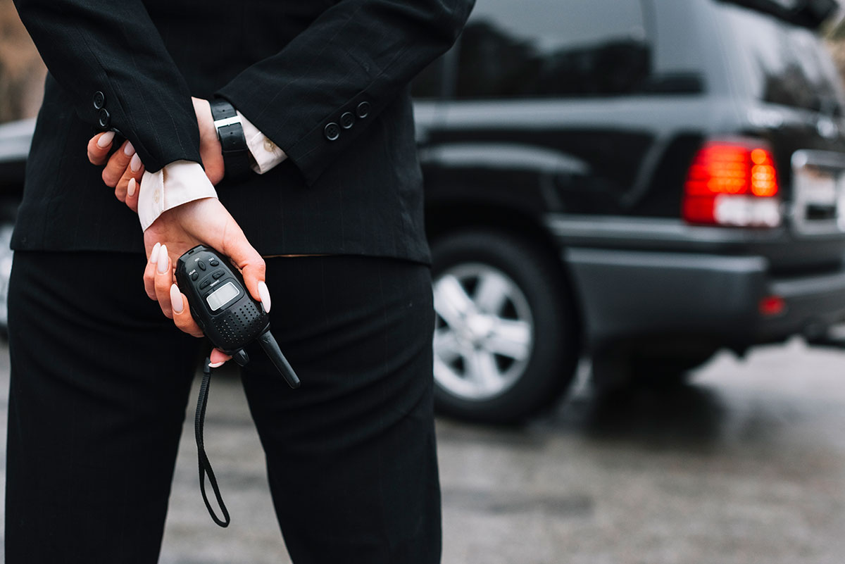 mujer de seguridad en traje, de espaldas con walkie talkie